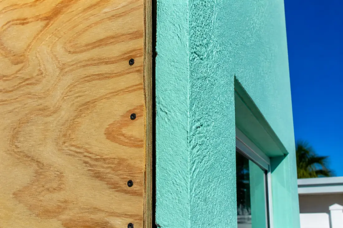 The fastened edge of a plywood panel against a masonry wall
