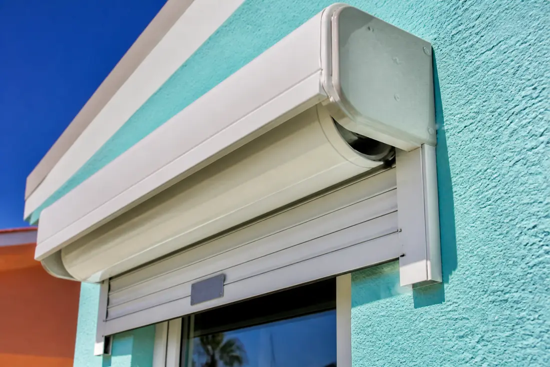 The underside of a roll-down shutter hood with the bottom slat visible beneath it
