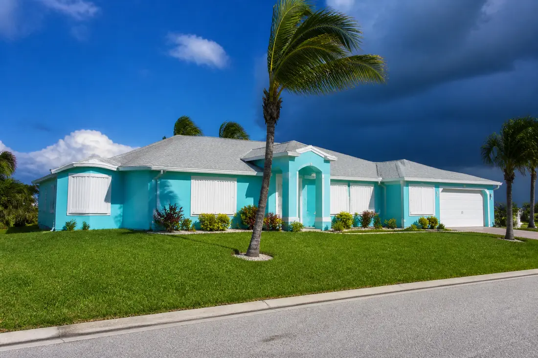 Accordion hurricane shutters closed across the windows of a Cape Coral house before a storm