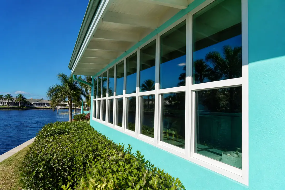 A line of aluminum-framed lanai windows under an existing roof overhang